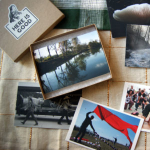 shot of open box set with postcards on display depicting photos of a river, a flag flying, a dance demonstration, and more