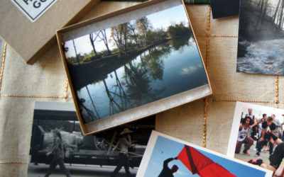 shot of open box set with postcards on display depicting photos of a river, a flag flying, a dance demonstration, and more