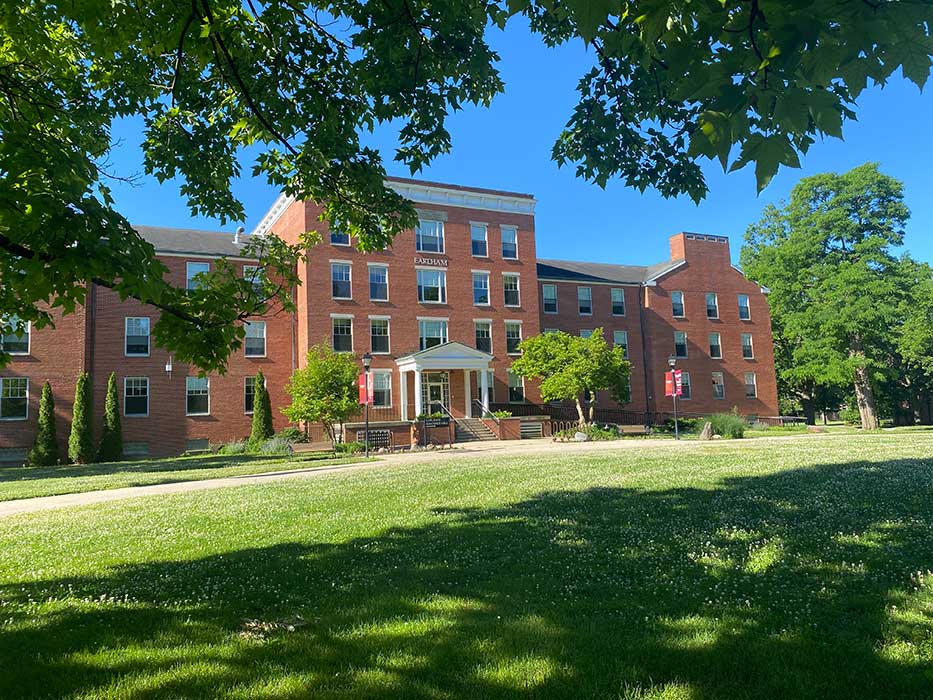Earlham Hall - brick residence hall with green lawn and trees in foreground