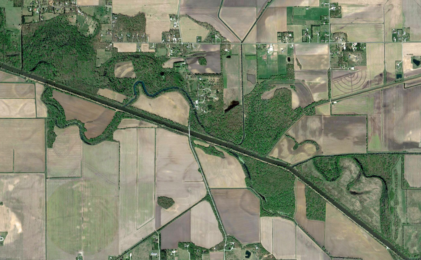 satellite image of baums bridge in porter county, Indiana: a straight line cuts from the upper left to bottom right of the frame, with a streamlike meander winding around it