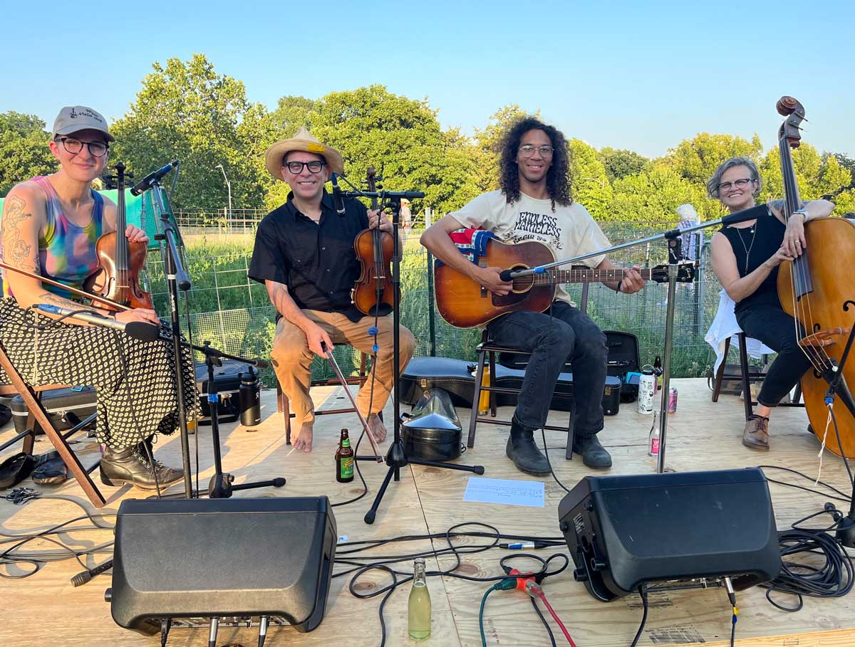 a string band of four people on an outdoor stage