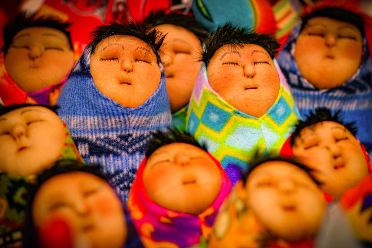 Indigenous dolls with sweet faces with closed eyes and black hair, wrapped in colorful shawls