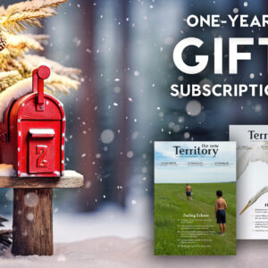 A snowy holiday scene in the background of a graphic that says "one-year gift subscription" with two copies of the handsome New Territory magazine pictured below the text.
