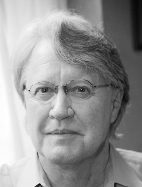 grayscale portrait of a white man looking kind and thoughtful, wearing glasses
