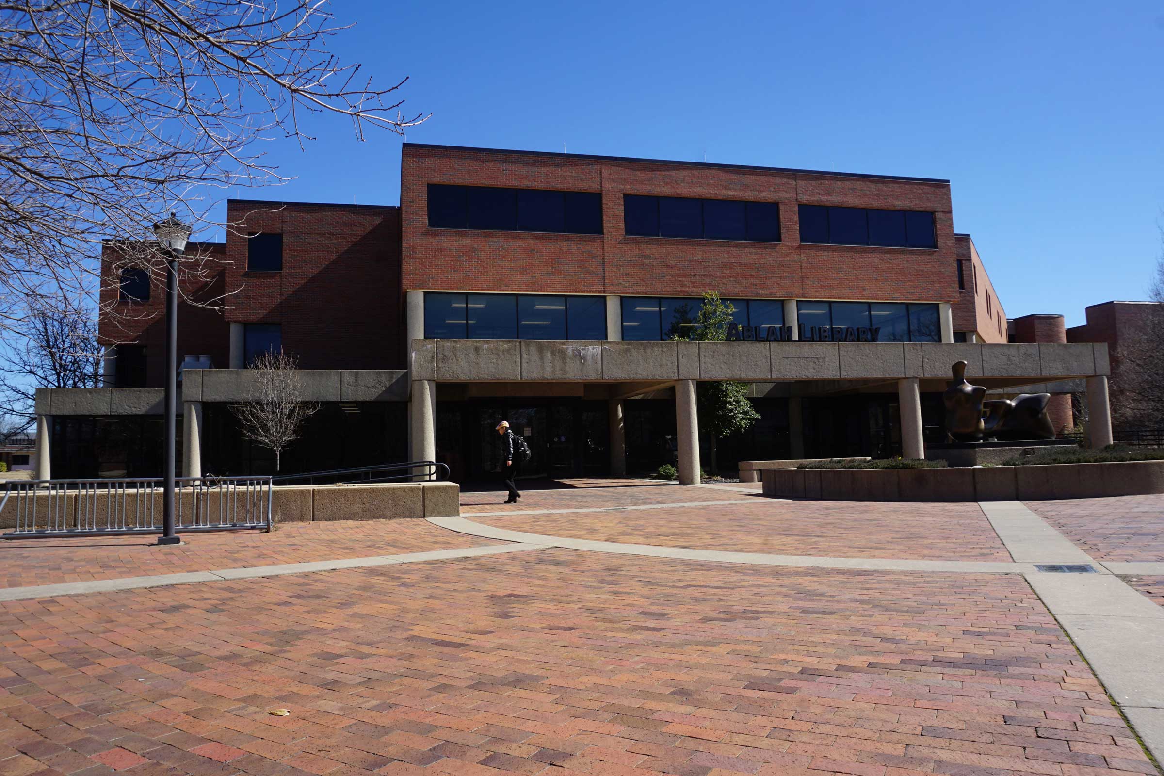 a blocky brick library building with brick mall space in front of it on a sunny day with blue sky
