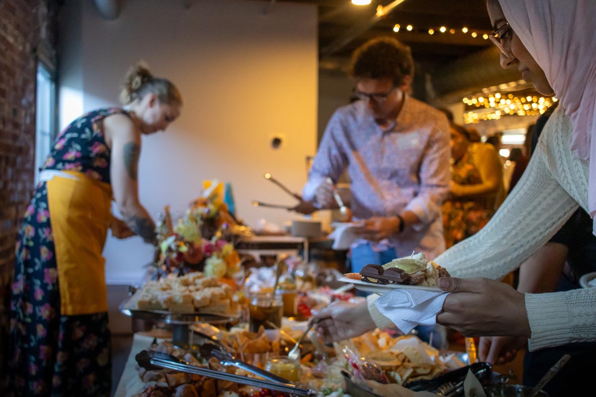 people serve themselves food at a fancy charcuterie table