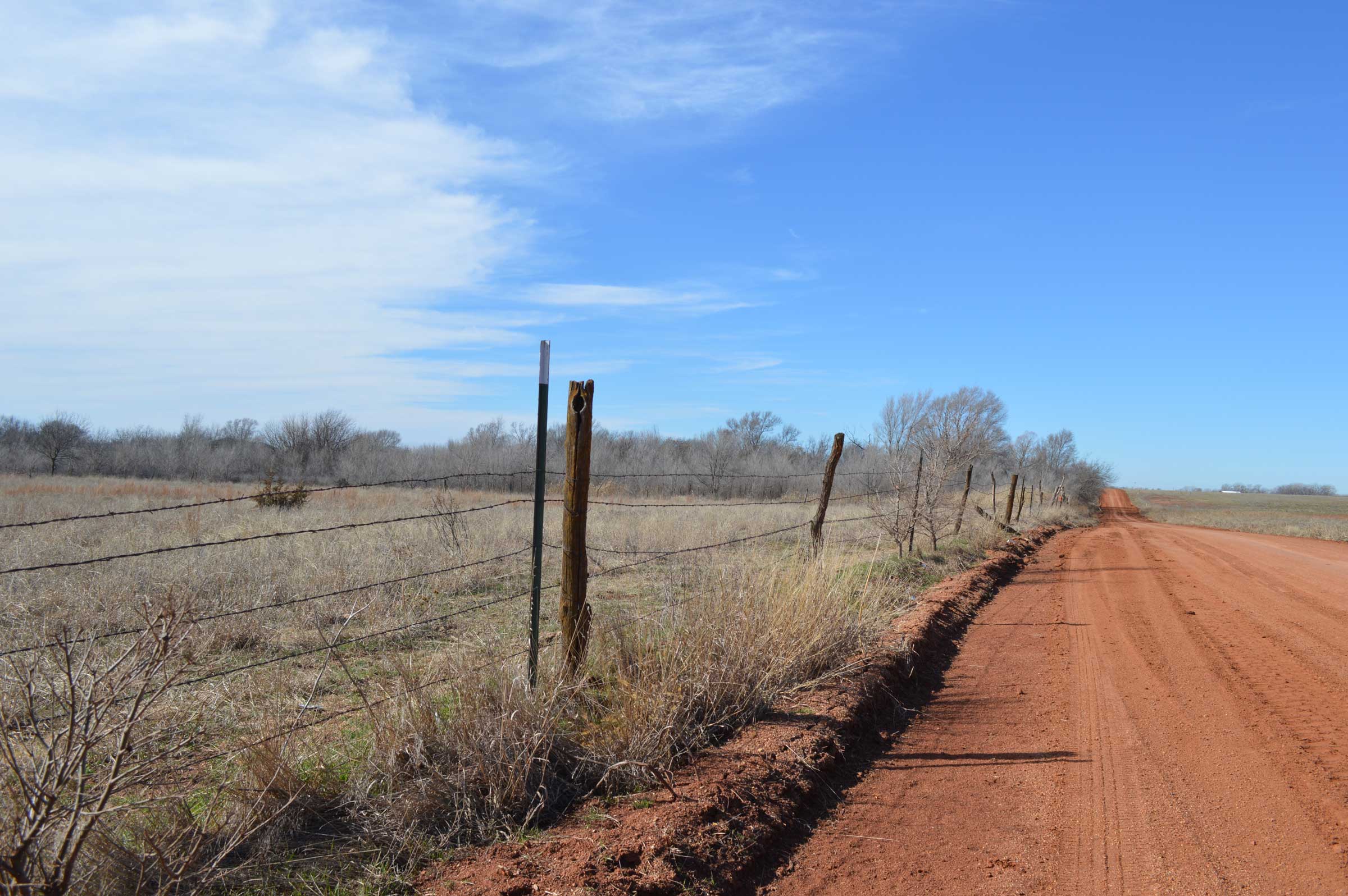 red dirt road and simple fence in vast landscape