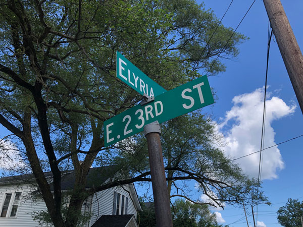 green street signs shot from below, showing corder of Elyria and E. 23rd St